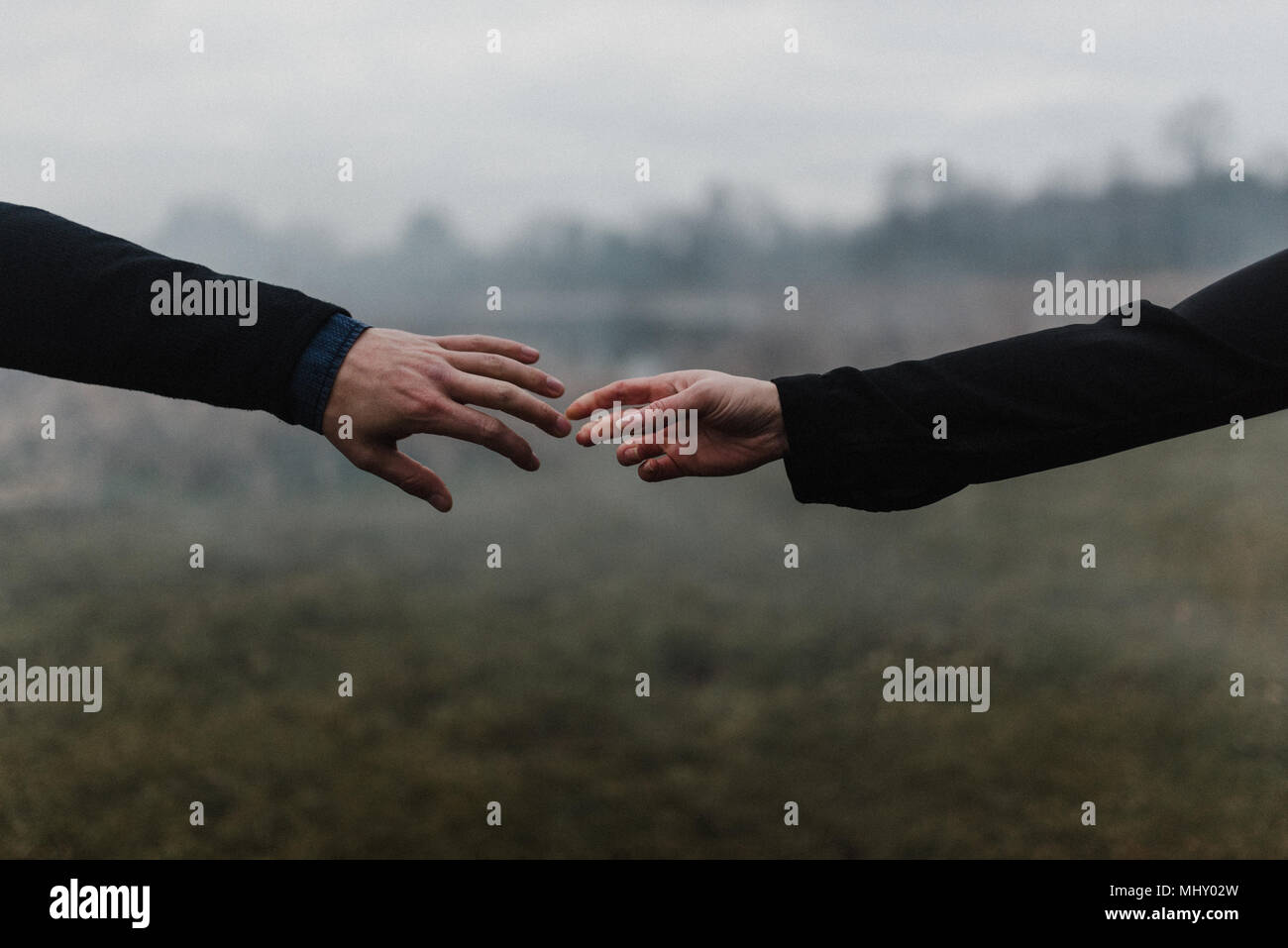 Vista ritagliata della coppia giovane tenendo le mani, dita toccano Foto Stock