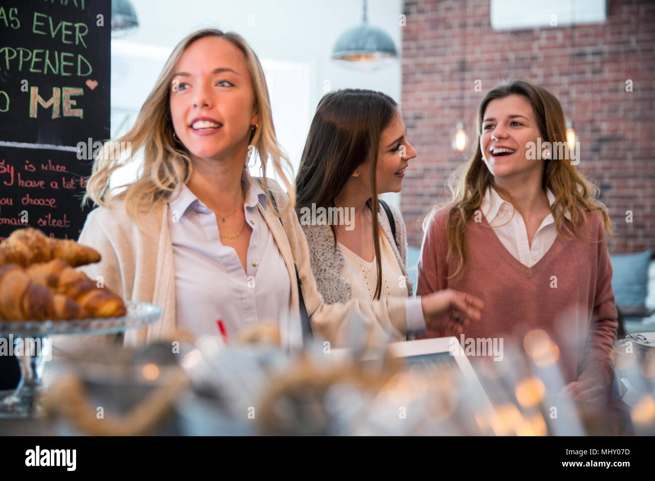 Tre amici di sesso femminile in cafe, in attesa di essere servito Foto Stock