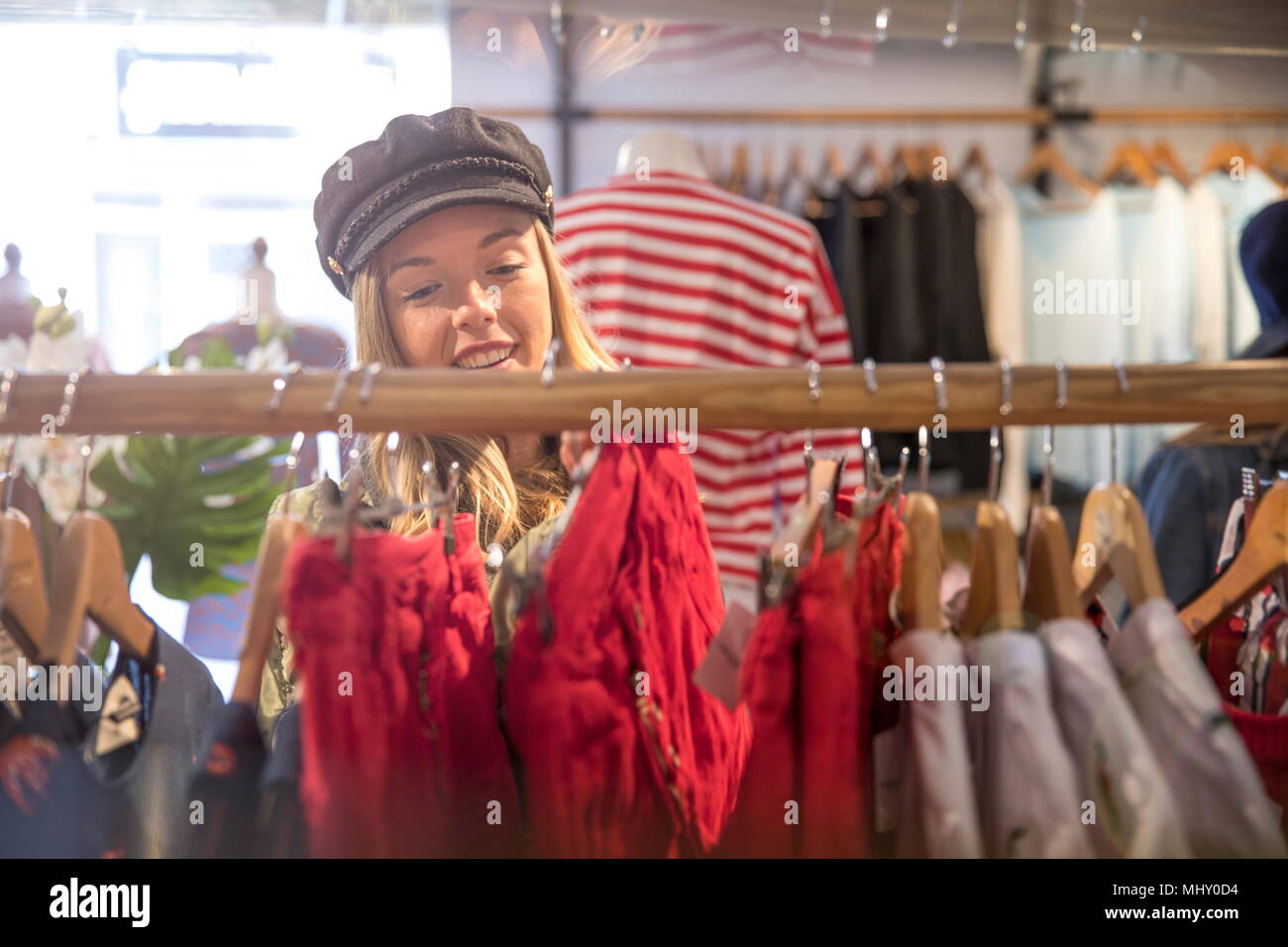 Giovane donna shopping, guardando i vestiti su rotaia in negozio Foto Stock