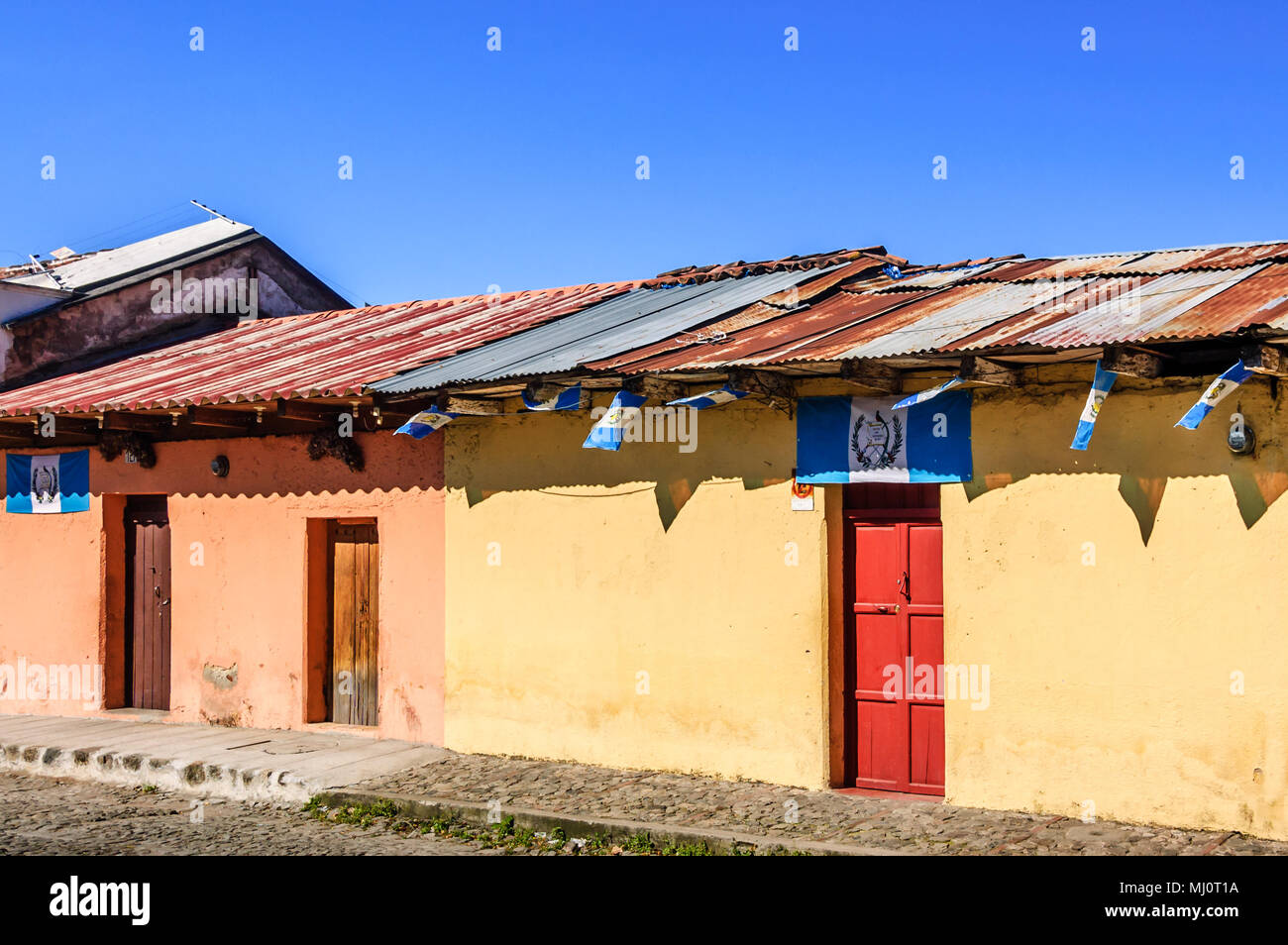 Antigua Guatemala - Ottobre 5, 2014: Vecchia, colorate case dipinte adornata con bandiere guatemalteco nel Patrimonio Mondiale dell Unesco di Antigua Foto Stock