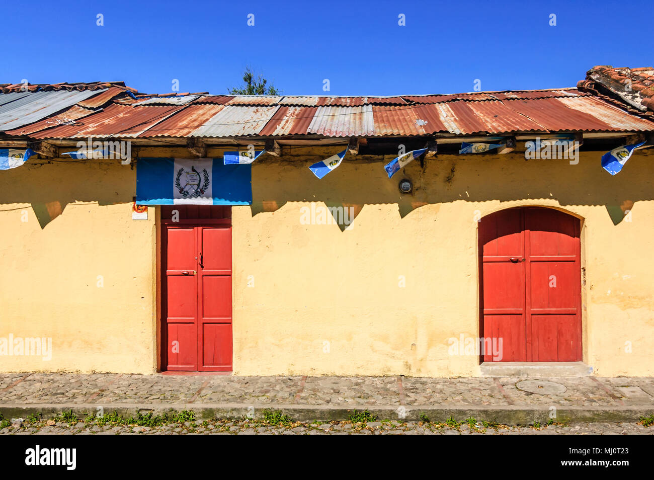 Antigua Guatemala - Ottobre 5, 2014: Vecchia casa dipinta adornata con bandiere Guatemalteca in città coloniale & UNESCO World Heritage Site di Antigua. Foto Stock