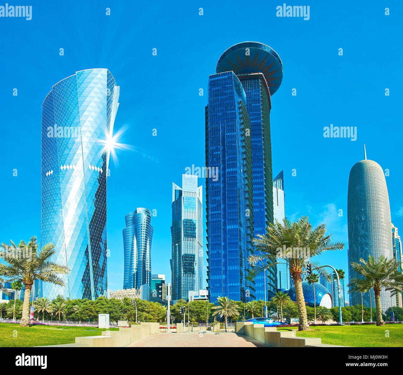 Panorama di grattacieli di Al Dafna business district, riflettendo il cielo blu e raggi di sole, West Bay, a Doha, in Qatar. Foto Stock