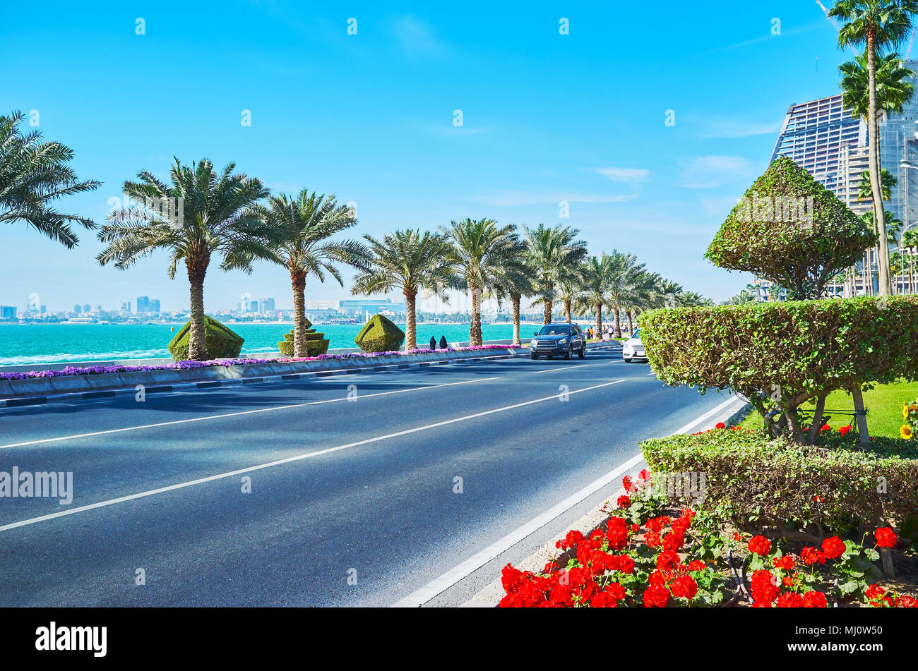 Corniche street in West Bay quartiere decorato con cespugli ornamentali, palme e aiuole fiorite, Doha, Qatar. Foto Stock