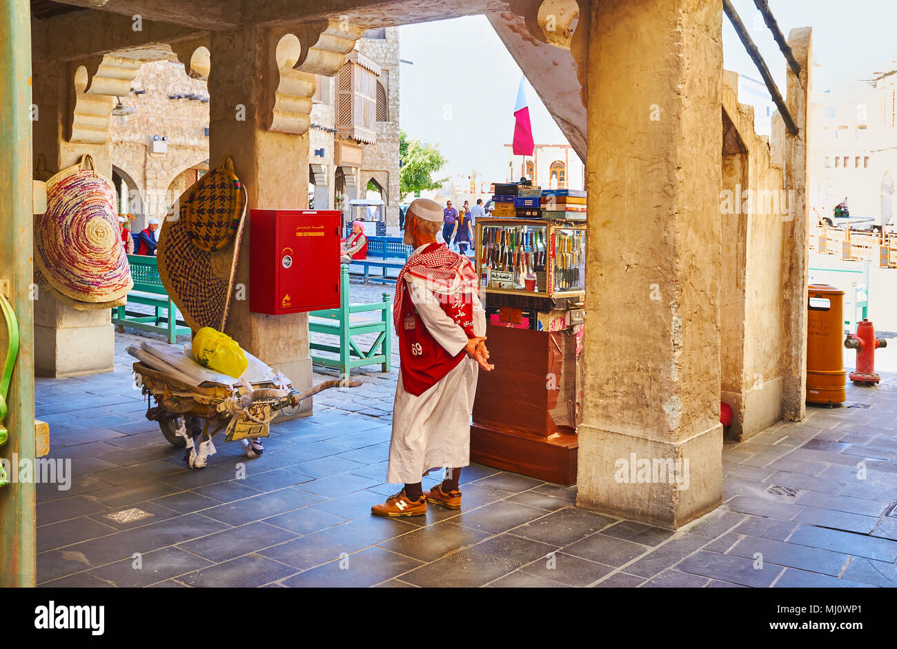 DOHA, Qatar - 13 febbraio 2018: Il portiere senior con il suo carrello attende il cliente presso il negozio in arcade di Souq Waqif, il 13 febbraio a Doha. Foto Stock