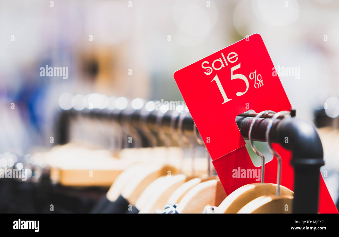 Rosso segno di vendita il 15% di sconto su rack di abbigliamento nel moderno centro commerciale o department store con copia spazio. Negozio di vendita al dettaglio evento promozionale concept Foto Stock