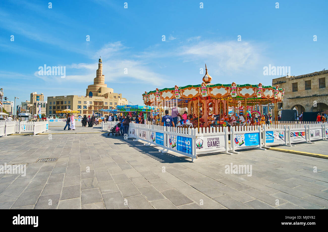 DOHA, Qatar - 13 febbraio 2018: in stile antico giostra nel luna park di Souq Waqif con minareto a spirale di Al Fanar moschea sullo sfondo, in Febbraio Foto Stock