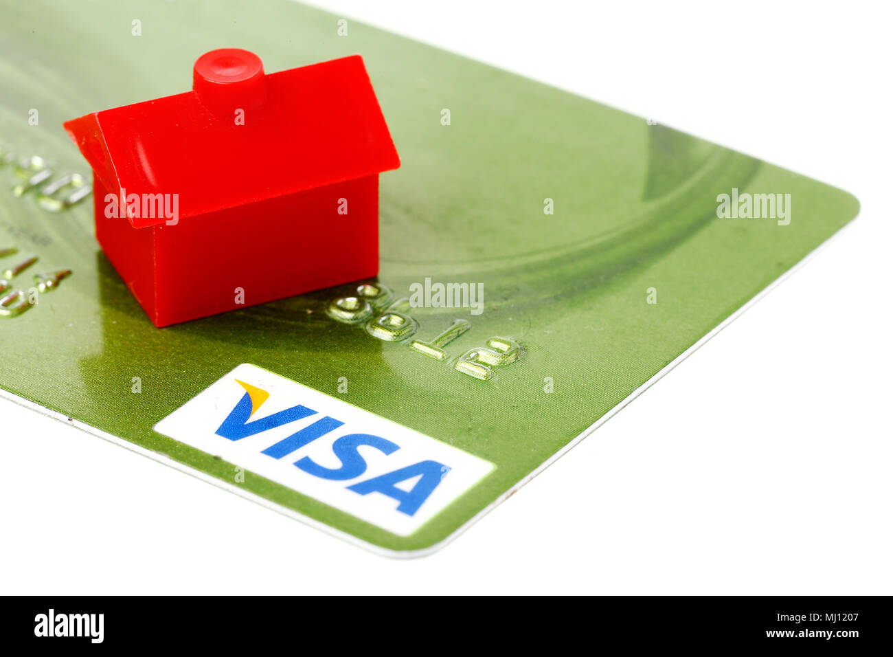 Una piccola casa rossa sul verde con la carta di credito VISA isolati su sfondo bianco. Foto Stock