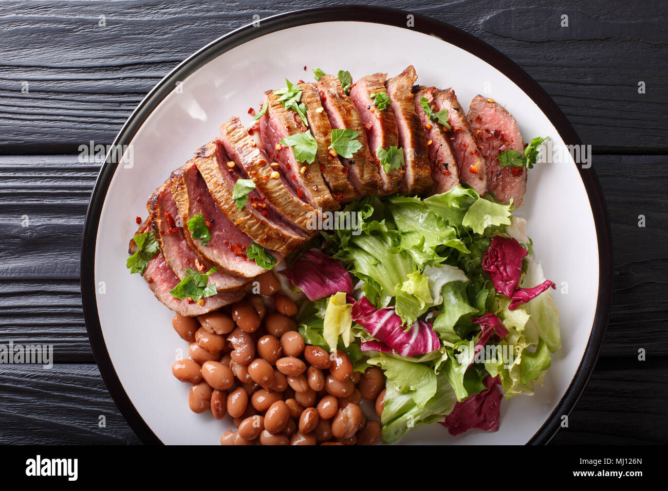 Grigliate di carne Asada bistecca con insalata di fagioli e close-up su una piastra. Parte superiore orizzontale vista da sopra Foto Stock