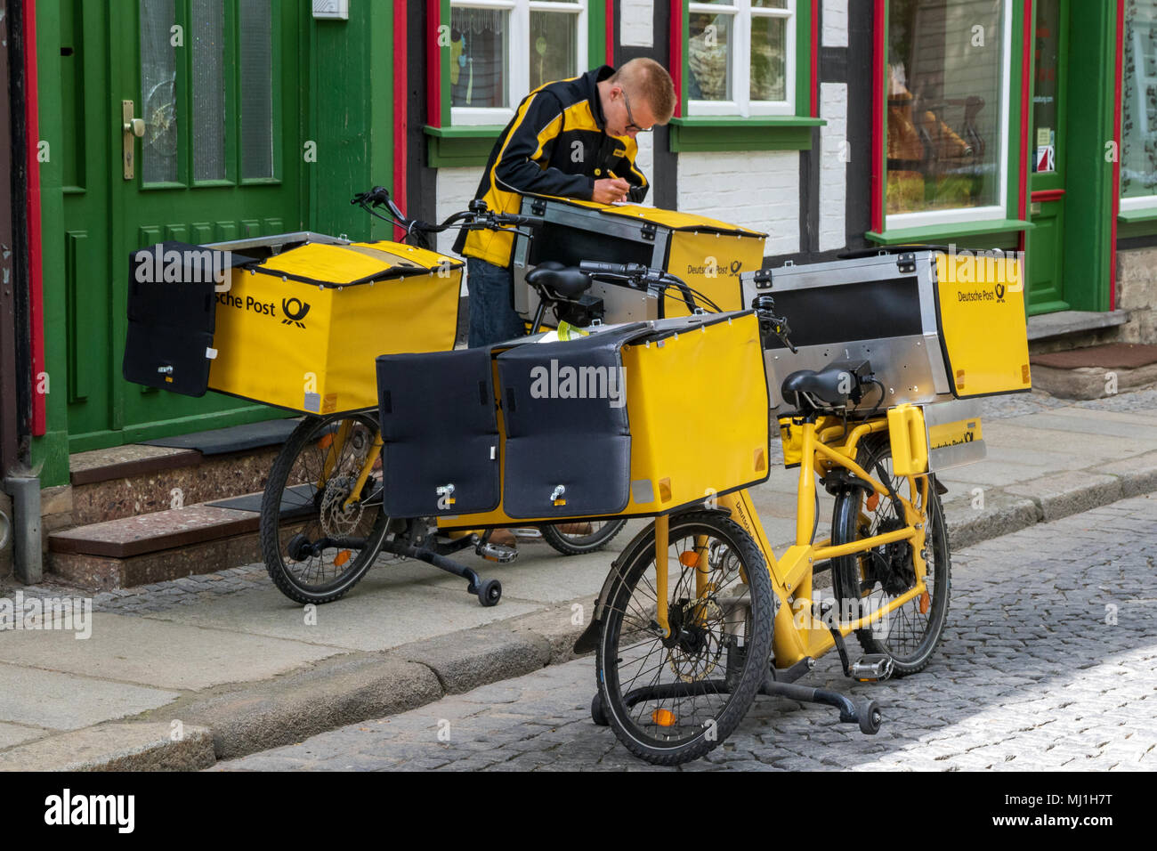 WERNIGERODE, Germania - 26 Aprile 2018: Tedesco postino della Deutsche Post consegna la posta utilizzando una bicicletta elettrica. Foto Stock