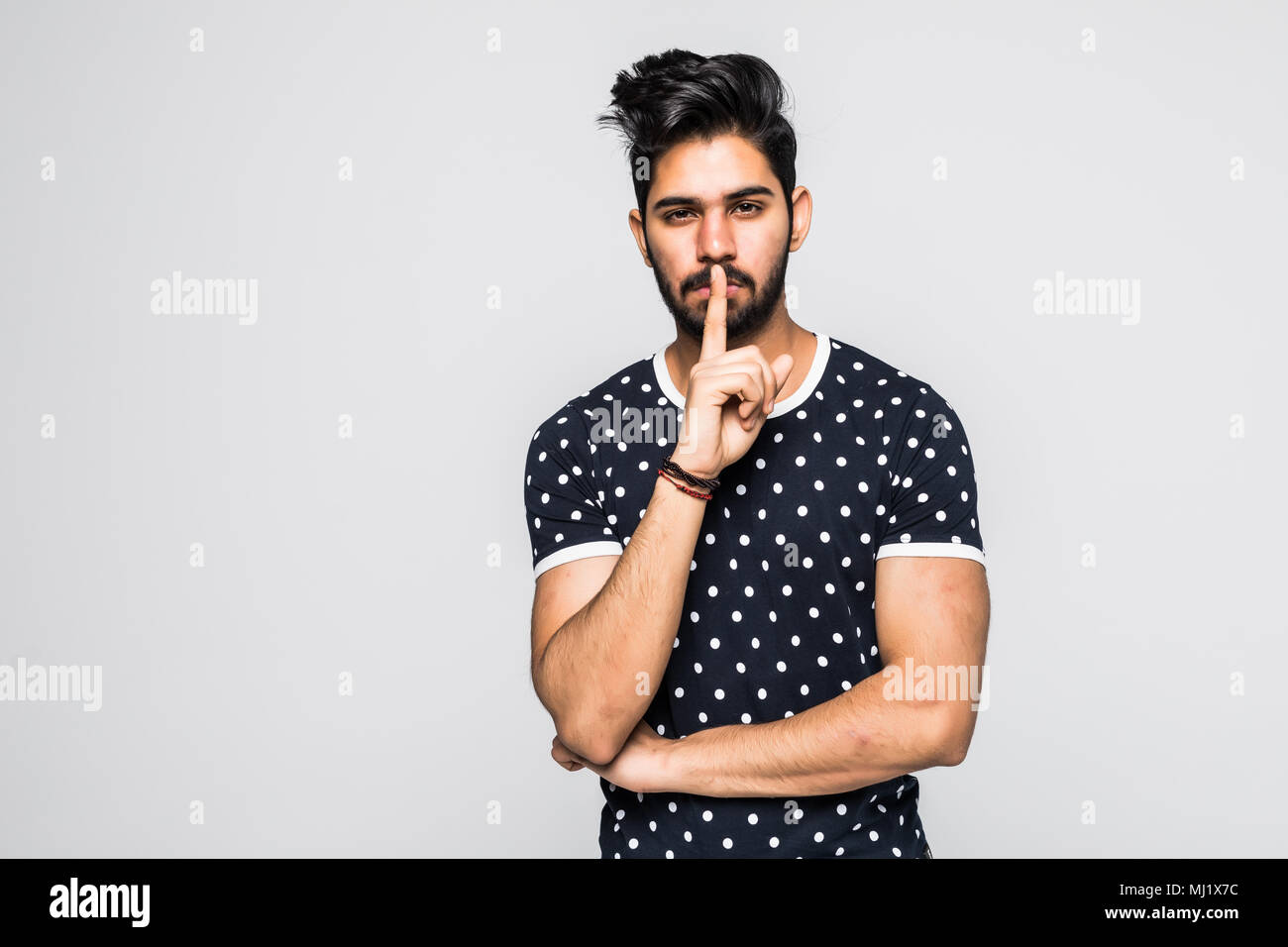 Giovane uomo di origine indiana con il suo dito indice sulle labbra Foto Stock
