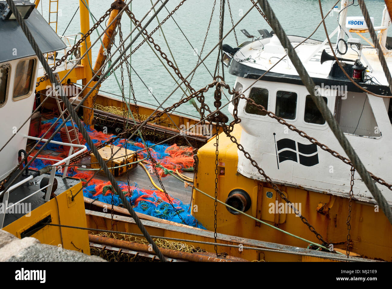 Un fascio trawler peschereccio che mostra il Cornish bandiera di San pirano, nonché reti colorati. Ormeggiata nel Porto di Newlyn UKs la più grande flotta di pesca. Foto Stock
