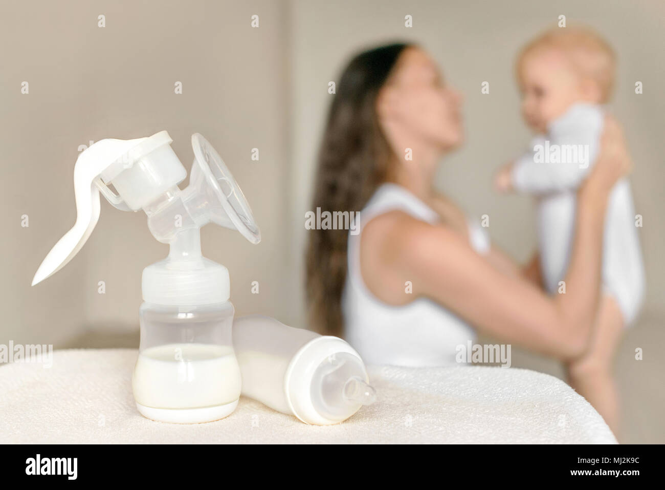 Tiralatte manuale e la bottiglia con il latte materno sullo sfondo della madre del bambino tiene nelle sue mani. La maternità e la cura del bambino. Foto Stock