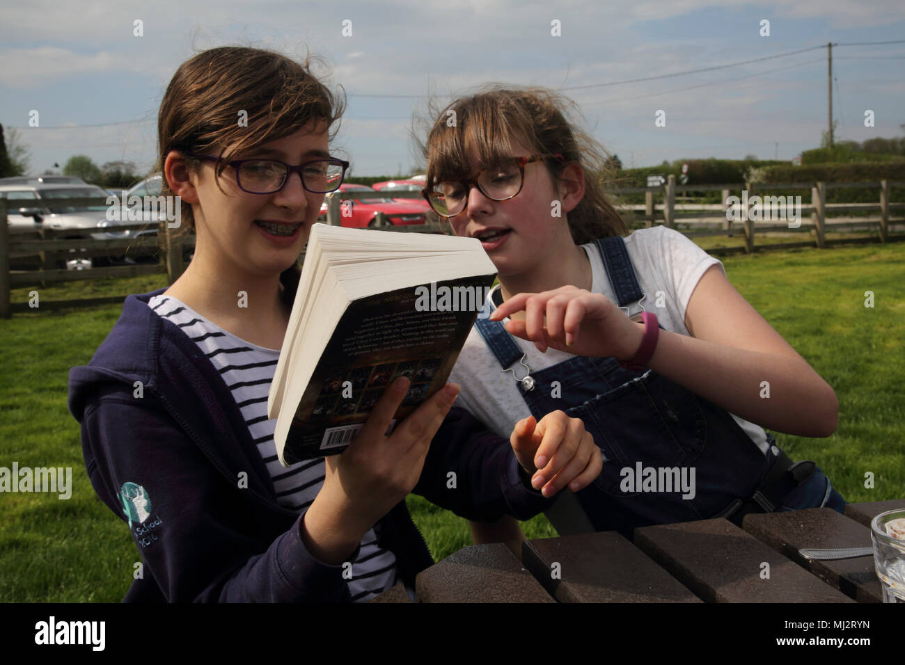 Lettura della ragazza a Suor seduta a tavola al di fuori di Gillingham Dorset Inghilterra Foto Stock