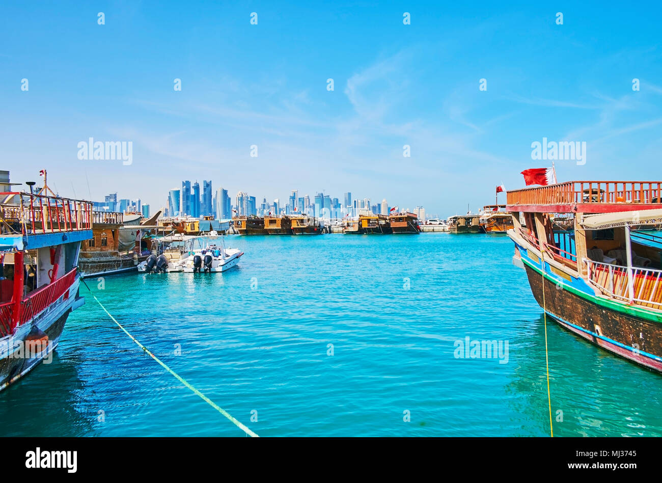 Il seascape di Doha con moltitudine di legno barche Dhow e grattacieli di West Bay dietro al porto, in Qatar. Foto Stock