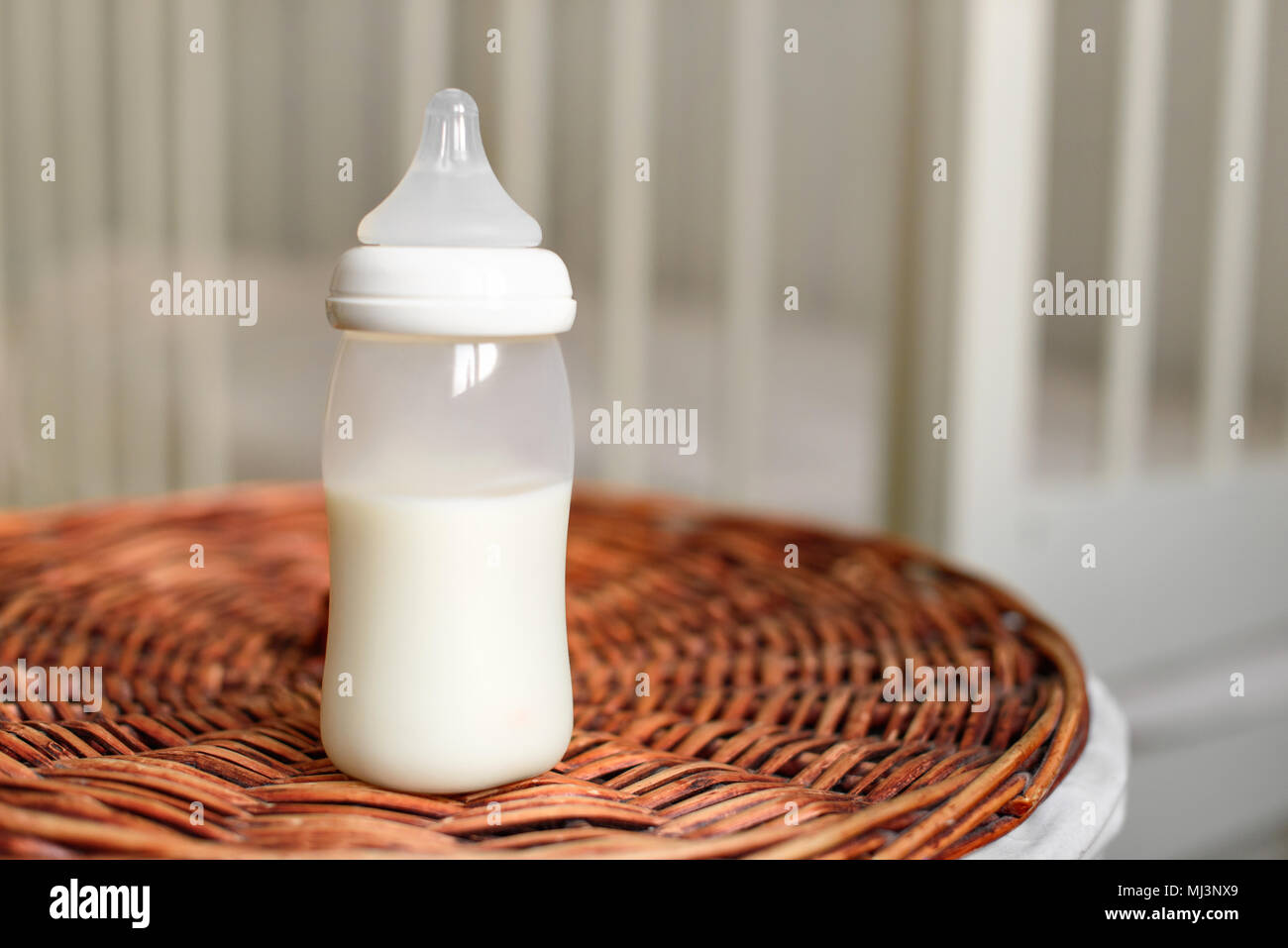 Bottiglia con latte per il bambino su un cesto di paglia. Bambini in camera con un letto matrimoniale. Foto Stock