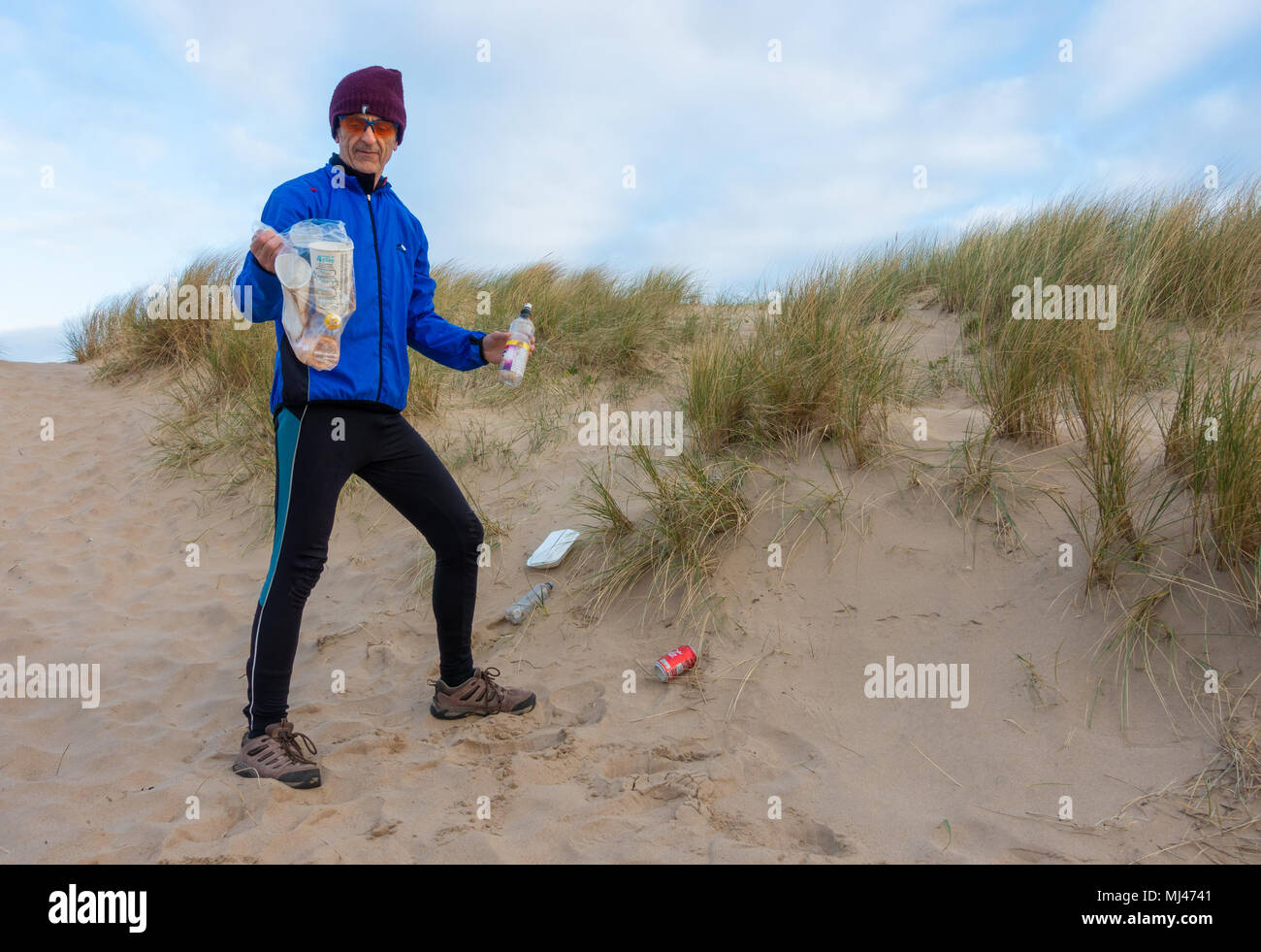 Un pareggiatore Plogging (prelievo di lettiera durante il jogging) sulla sua corsa mattutina attraverso le dune di sabbia.UK Foto Stock