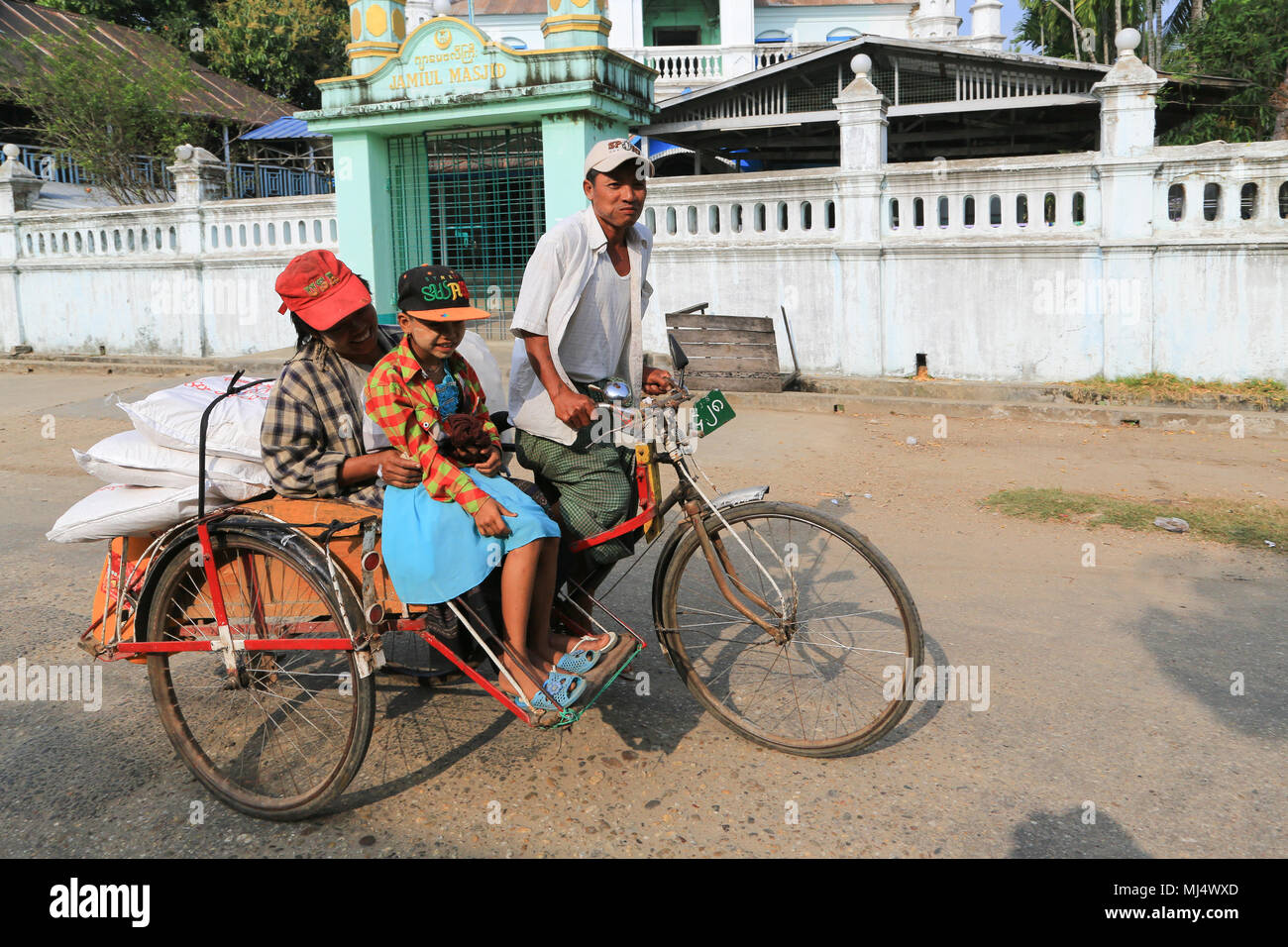 Un tri-shaw conducente di trasportare i suoi passeggeri e la loro shopping a Maubin, una città sul fiume Myitmaka, nel delta di Irrawaddy, Myanmar (Birmania). Foto Stock