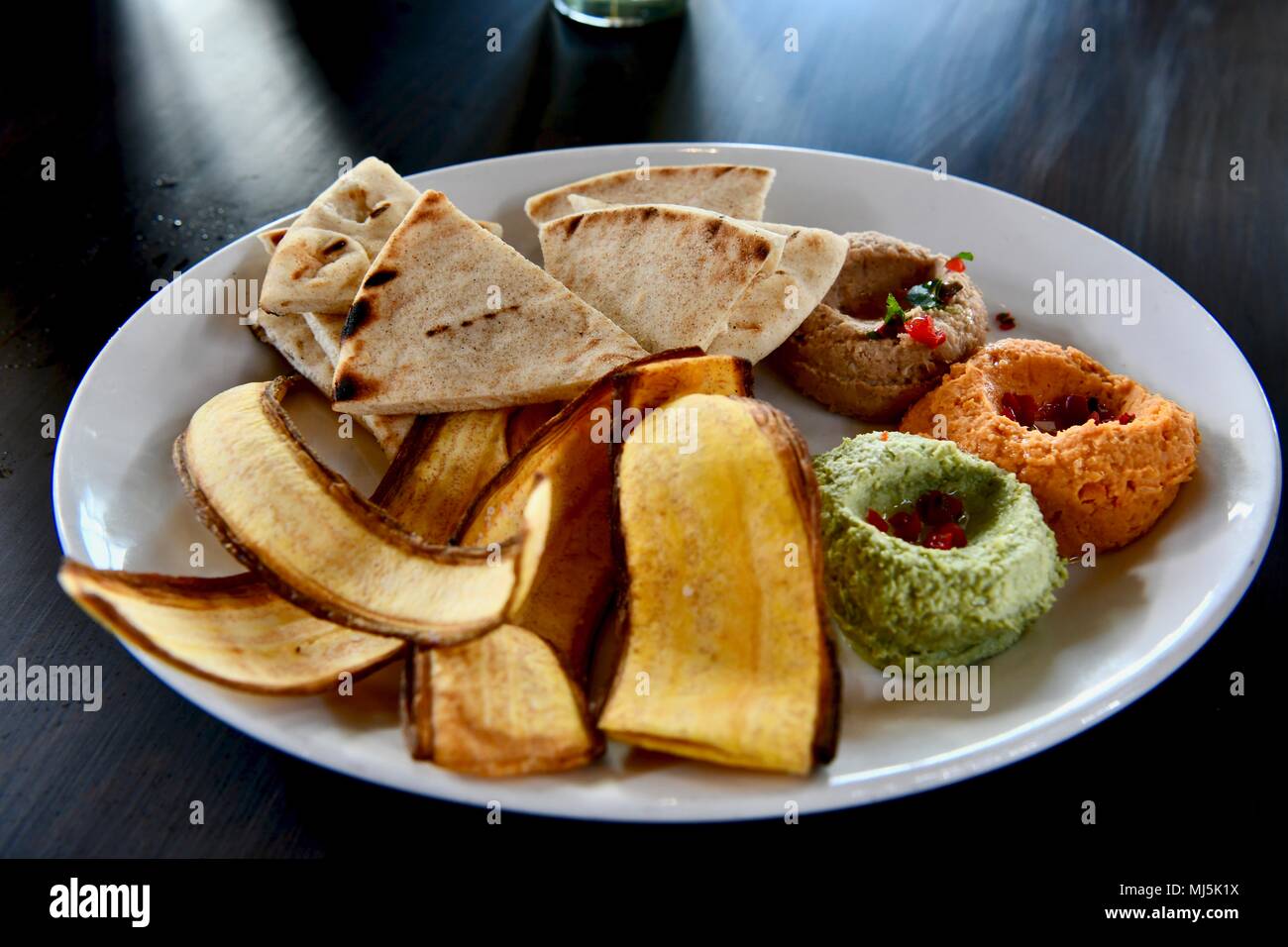 Hummus servita con pane pita e banana chips Foto Stock