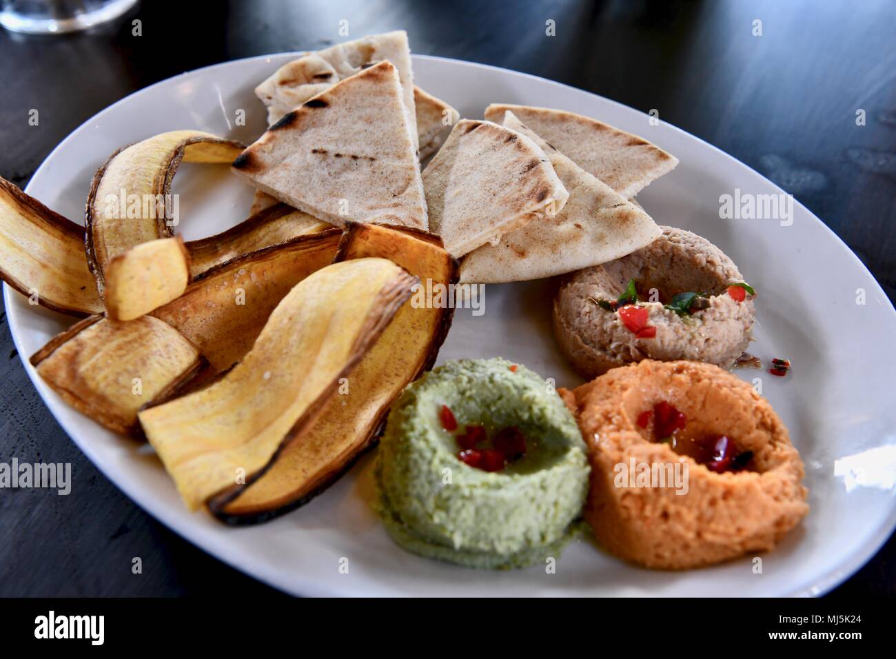 Hummus servita con pane pita e banana chips Foto Stock