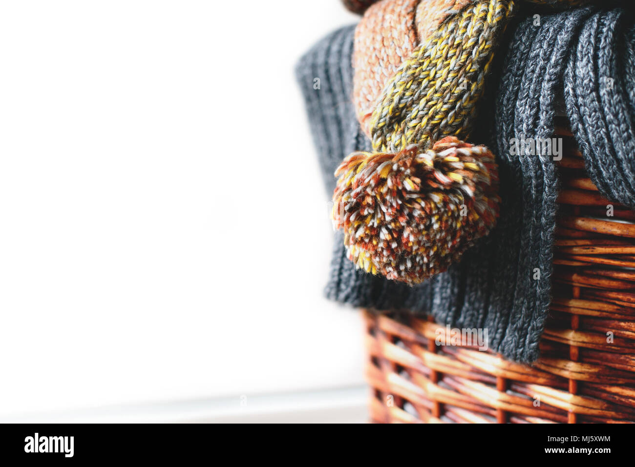 Pila di maglia sciarpe invernali sul cesto di paglia isolati su sfondo bianco. Copia gratuita dello spazio. Foto Stock