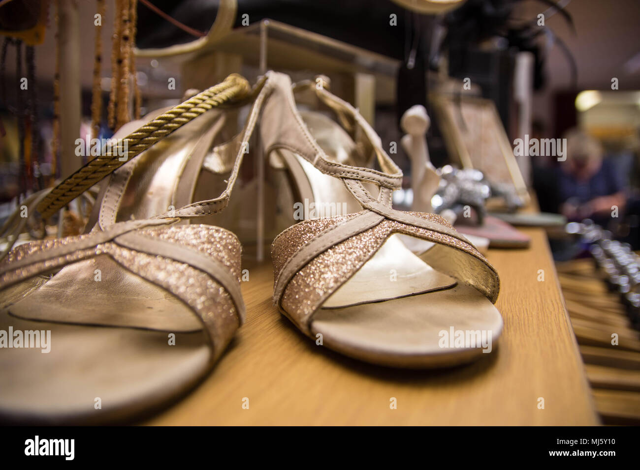 Una coppia di oro donna sandali di sera in un negozio di Banbury, Regno Unito Foto Stock