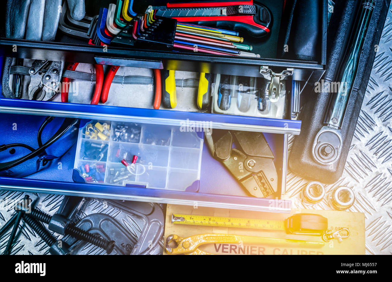 Vista superiore di strumenti nella casella sulla piastra a scacchi background in officina. Attrezzi di servizio impostato. Home la struttura e gli strumenti elettrici. Plumber utensili a mano. Technic Foto Stock
