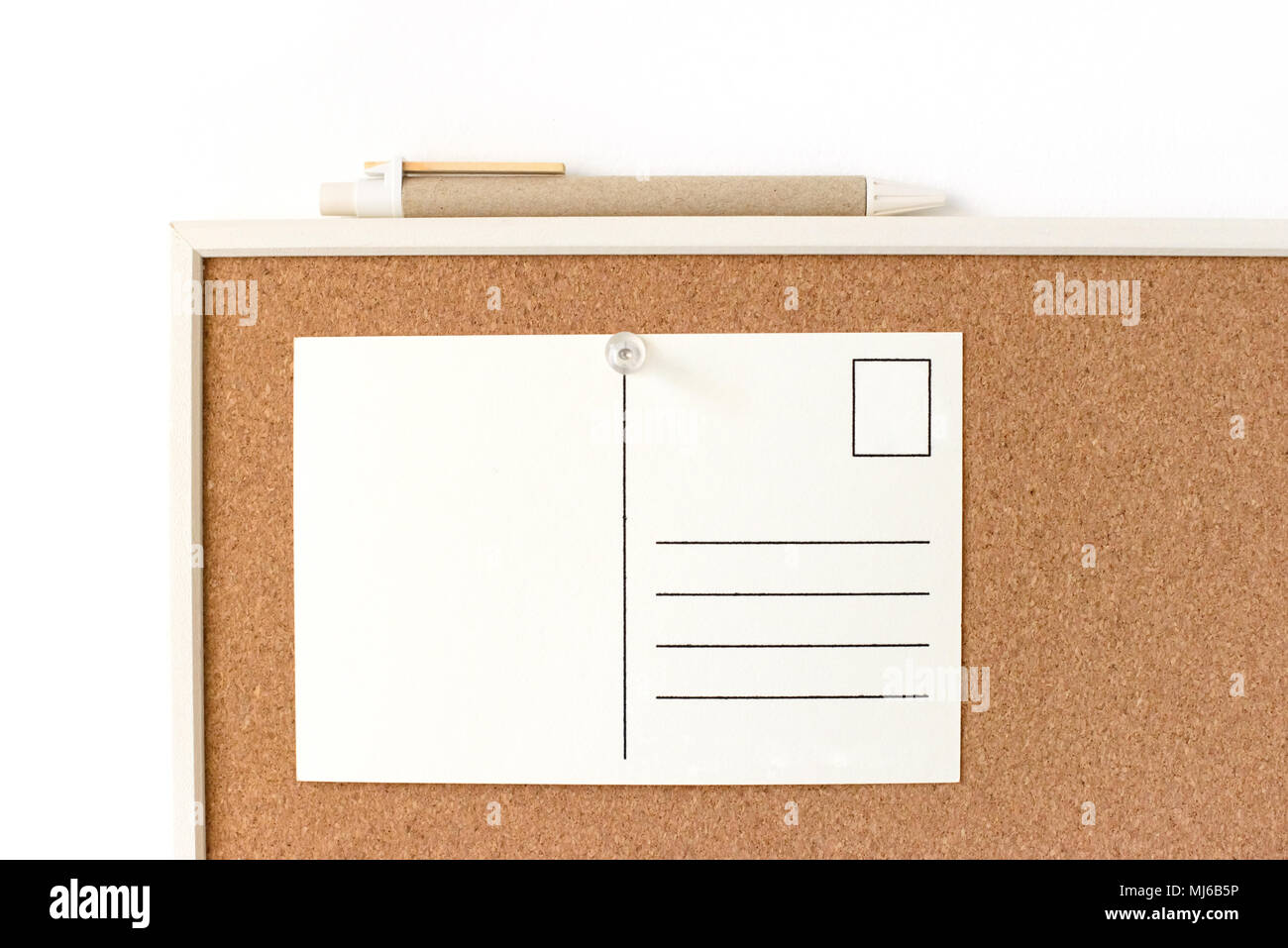Cartolina bianco con copia gratuita spazio appuntato sulla bacheca di sughero su una parete. In ufficio o a scuola concetto. Foto Stock