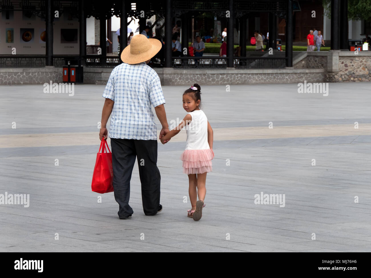 Uomo cinese a piedi con bambina e tenendo le mani in Tianshui, provincia di Gansu, Cina e Asia Foto Stock