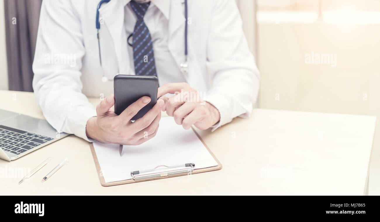 Medico di lavoro e di ricerca di informazioni su mobile presso l'ufficio. Trattamento e concetto tecnologico. Foto per aggiungere messaggio di testo. Sfondo per art design Foto Stock