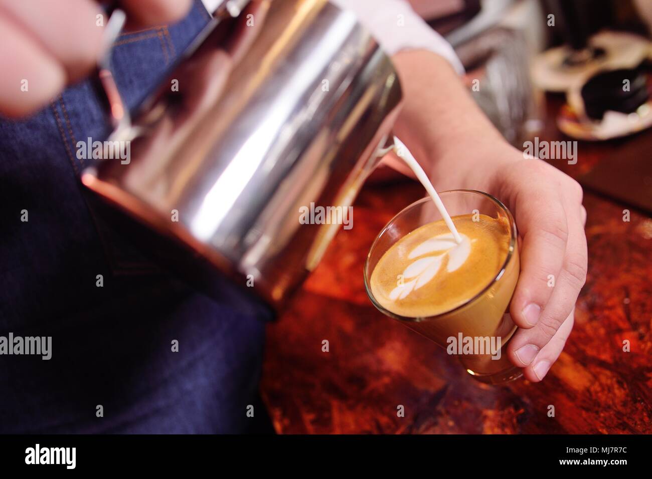 Caffè barman prepara il caffè con un disegno sulla gomma espansa o latte-art Foto Stock