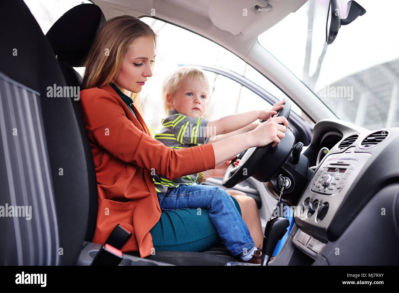 Madre con un bambino piccolo si siede dietro al volante di un'auto. Viaggio  di famiglia Foto stock - Alamy