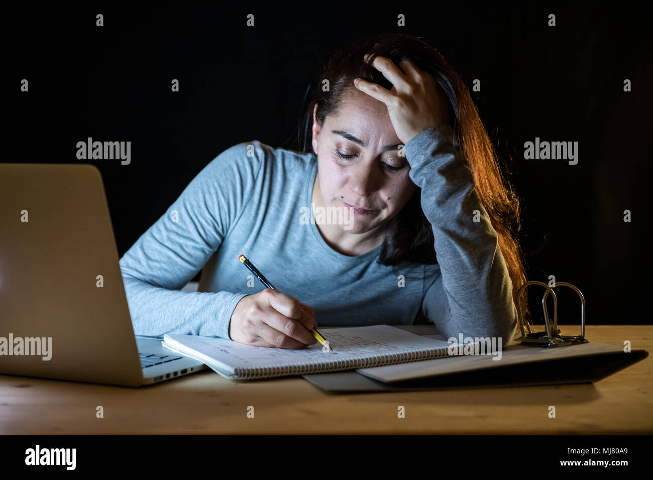 Affaticati e stanchi studentessa di funzionare la scorsa notte sul suo computer portatile e cercando di non cadere addormentato in un percorso di studio per l'ultimo anno di un corso di concetto dell'esame. Foto Stock