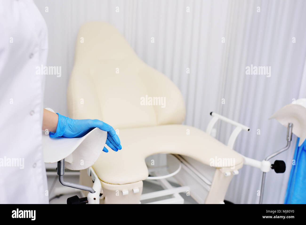 Il medico la mano in una gomma guanto igienico su una sedia ginecologica. Le donne di consultazione Foto Stock