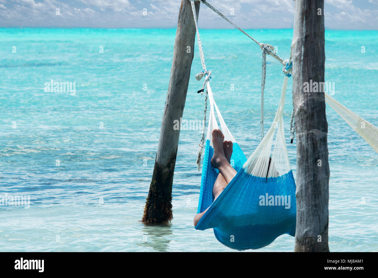 Rilassatevi sulla spiaggia in amaca, vista di gambe e mare tropicale Foto Stock