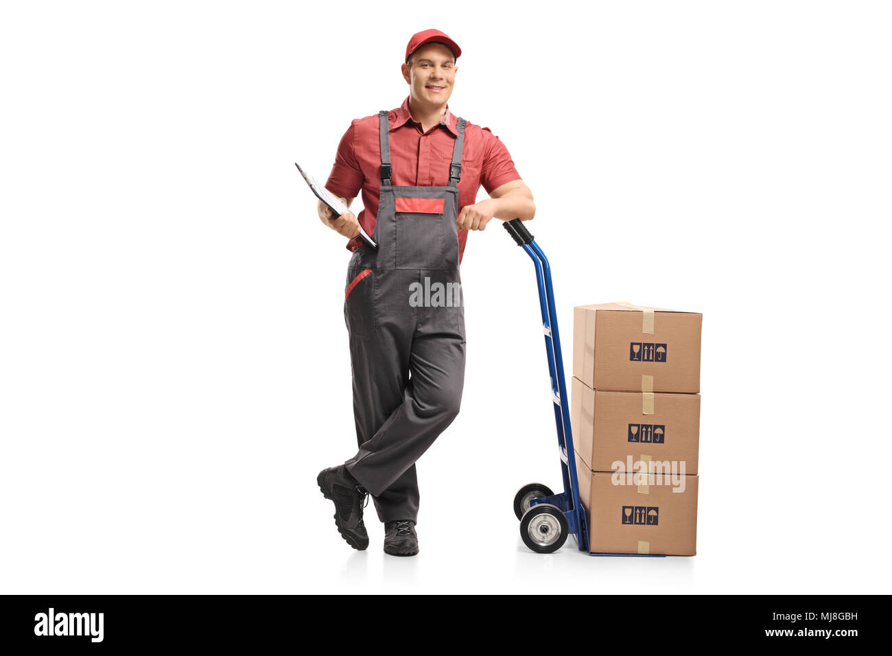 A piena lunghezza Ritratto di un mover con un fermaglio poggiante su un carrello con una pila di scatole isolate su sfondo bianco Foto Stock