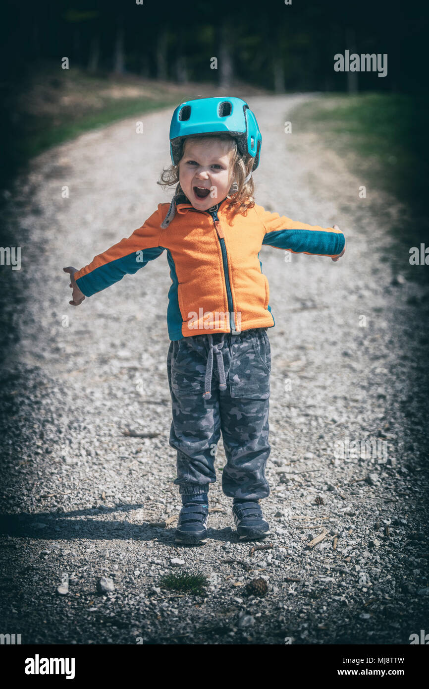 Piccolo bambino femmina con casco urlo sulla strada rurale lomo foto di stile Foto Stock