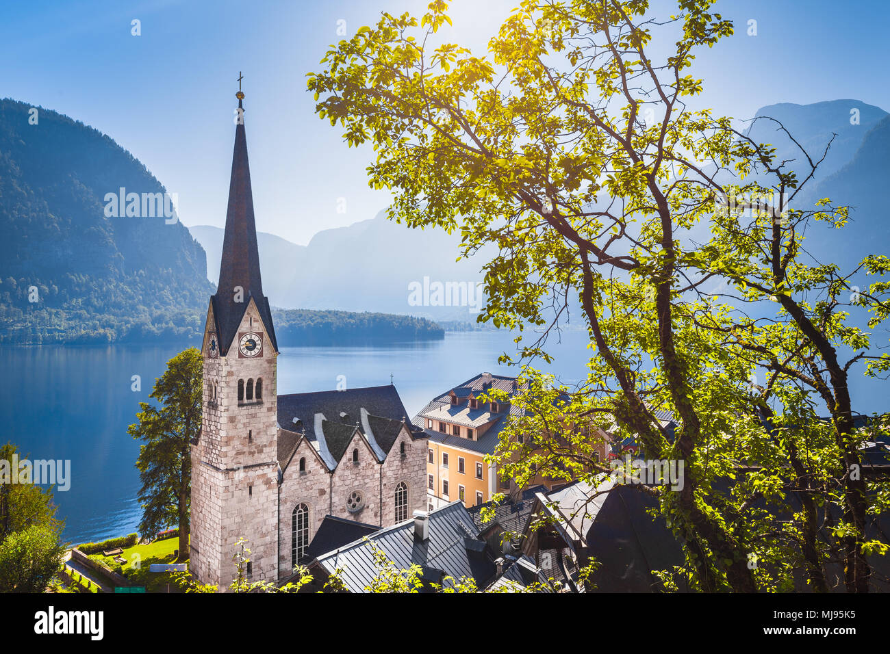 Classic vista da cartolina famosa Hallstatt Lakeside Town nelle Alpi con chiesa storica torre in scenic golden. La luce del mattino in una splendida giornata di sole Foto Stock