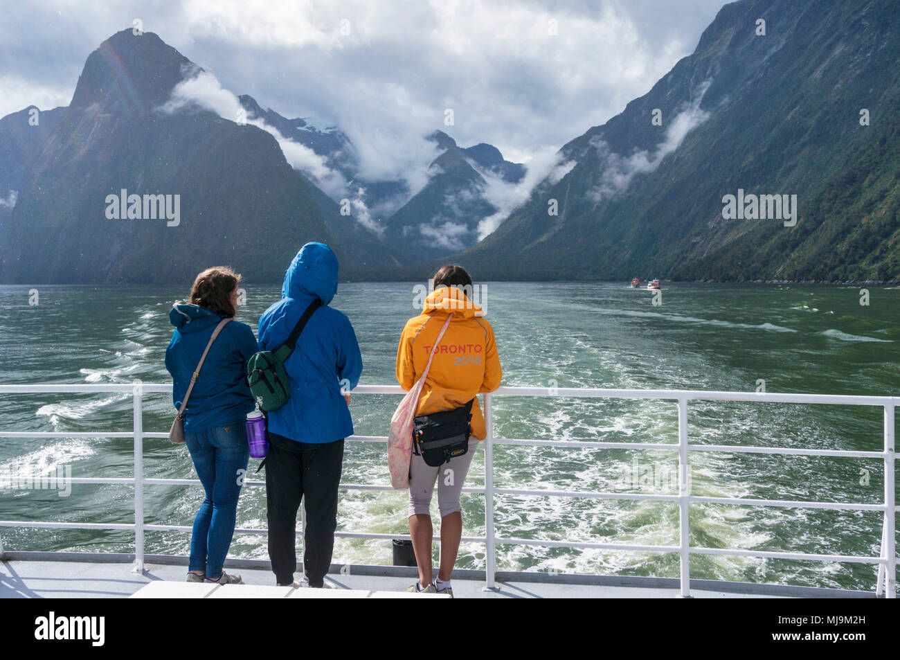 Milford Sound Nuova Zelanda Milford Sound tre amici si fermò a prua di una barca per gite di ritorno da un viaggio in barca sul Milford Sound Isola del Sud Foto Stock