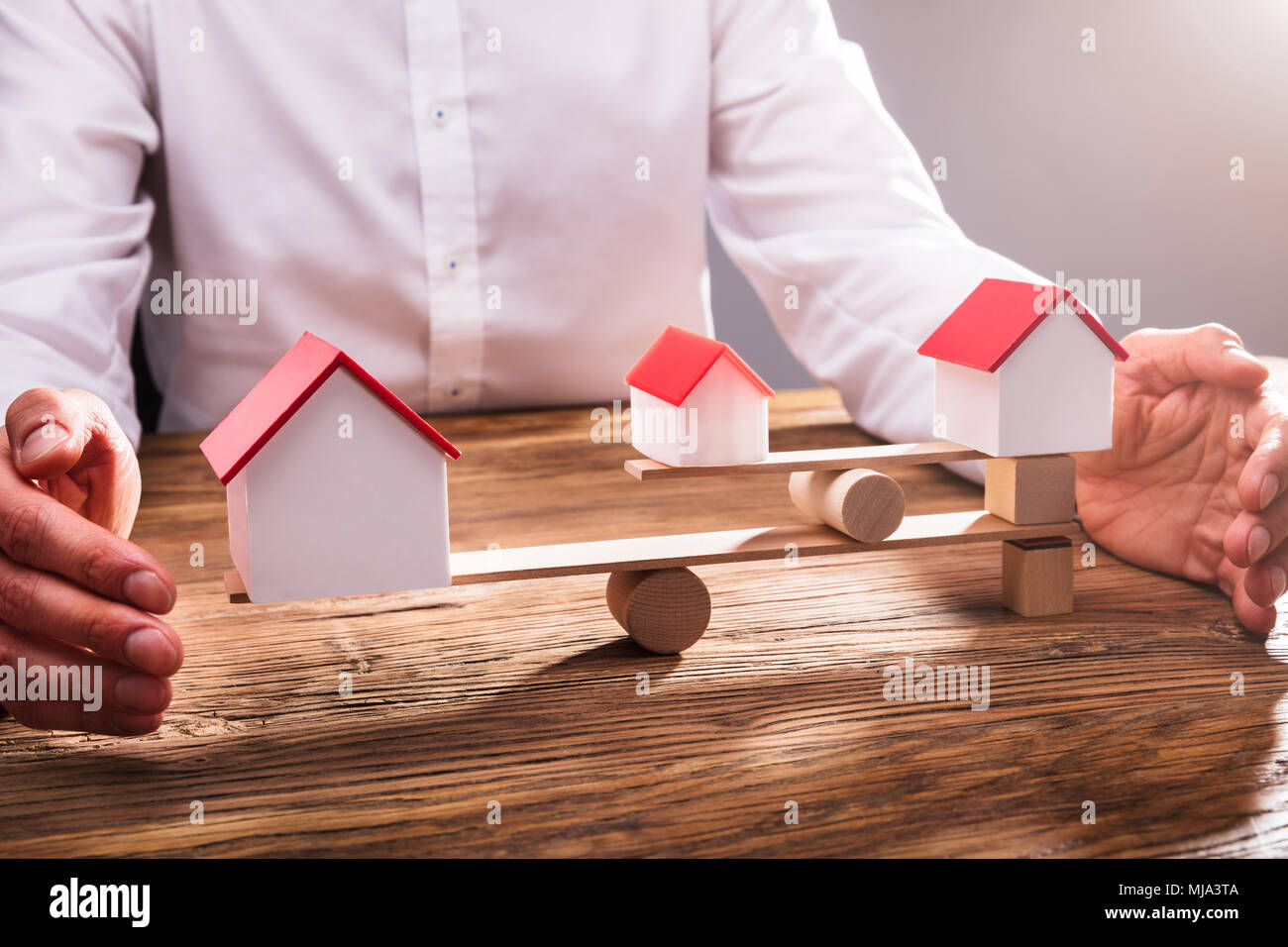 Close-up di commercianti la mano che copre l'equilibrio tra il modello di casa su altalena in Office Foto Stock