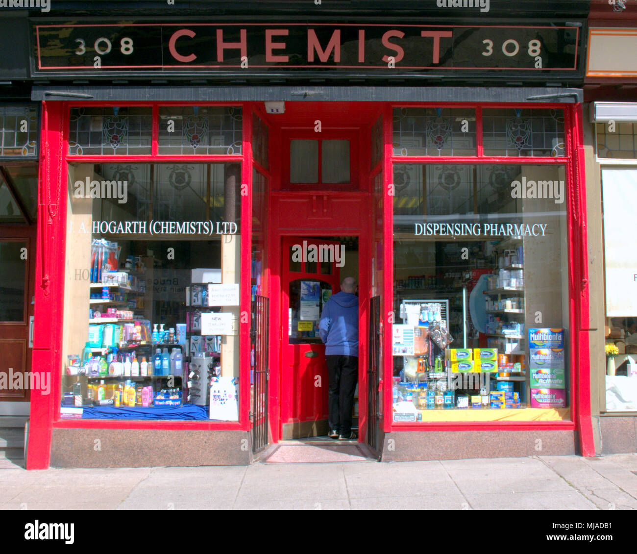 Tradizionale farmacia con facciata d'epoca con un gentiluomo il cliente inserendo la porta anteriore visto dalla strada in una giornata di sole Foto Stock