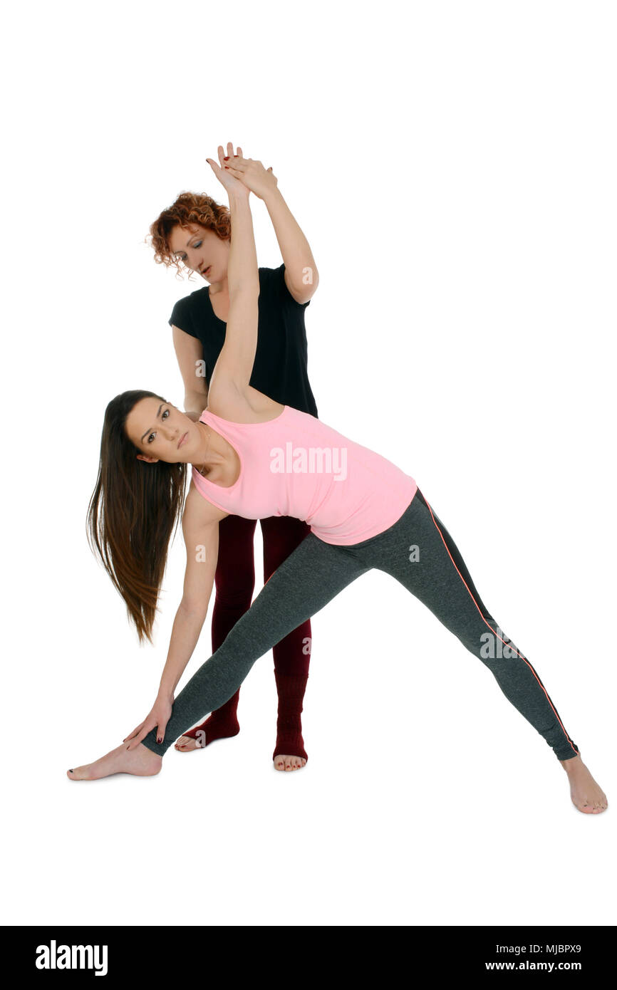 Insegnante di Yoga mostra come mettere una giovane ragazza di colore bianco nella posizione di Yoga triangolo esteso pongono in sanscrito Utthita Trikonasana. Foto Stock
