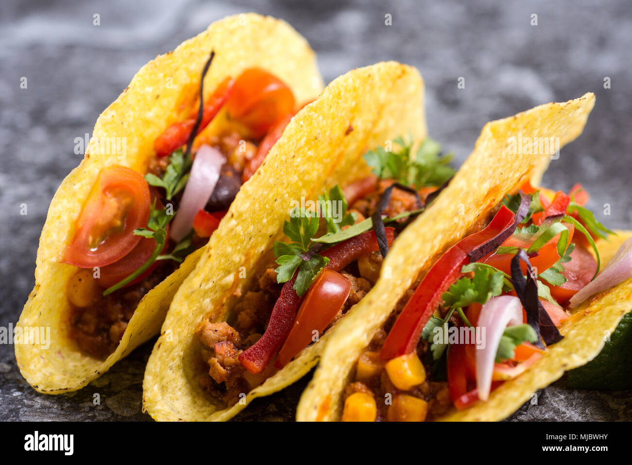 Tre colorate Tacos messicani in gusci su sfondo di pietra Foto