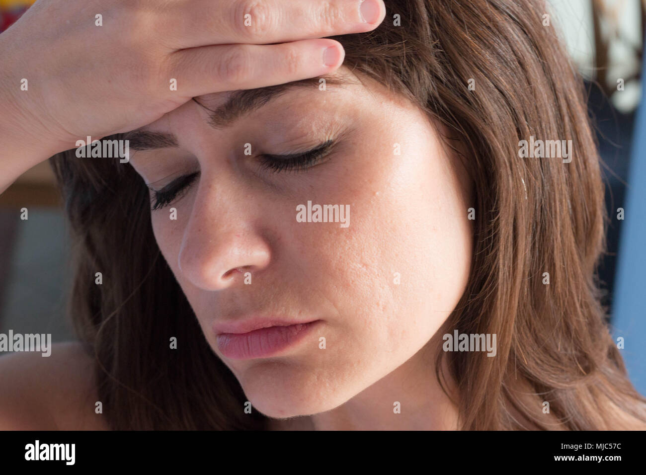Close up ritratto di soggetti di razza caucasica giovane donna con gli occhi chiusi e la mano sulla fronte come avente un mal di testa. Foto Stock