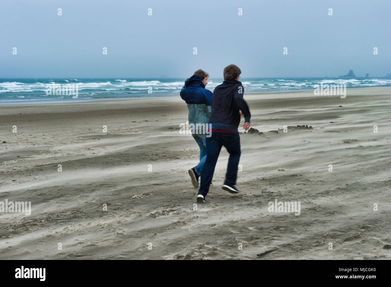 Due fratelli coraggioso il vento freddo umido meteo a Cannon Beach sulla costa dell'Oregon Foto Stock