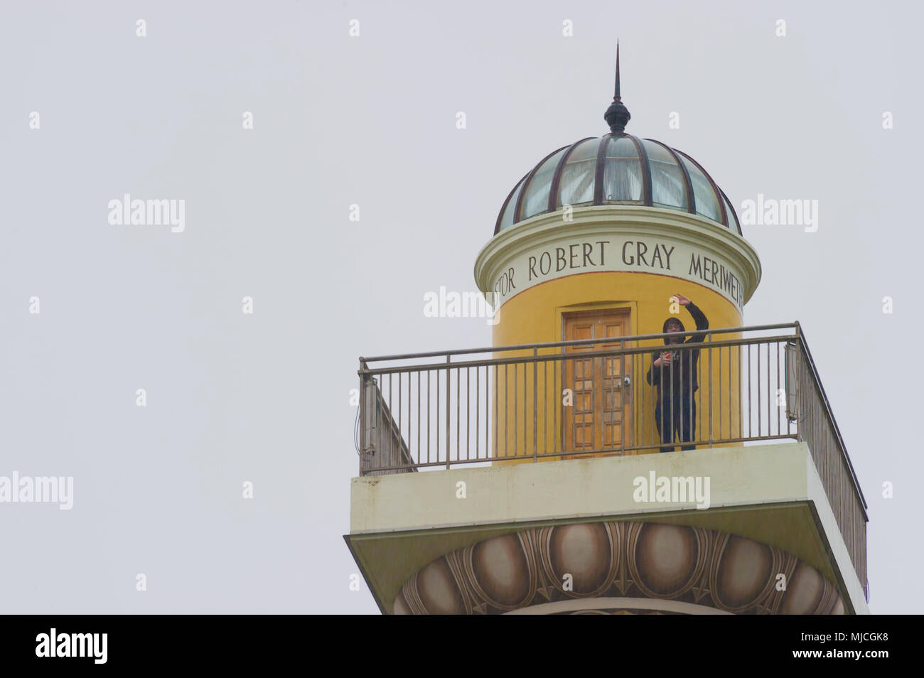 Astoria, Oregon, Stati Uniti d'America - Aprile 5, 2018: un uomo onde per il fotografo di seguito dalla parte superiore del ponte di osservazione dell'Astoria colonna un ben noto lan Foto Stock
