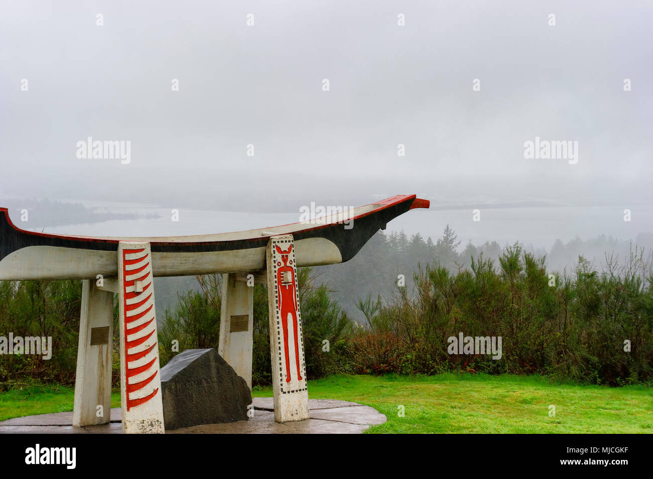 Astoria, Oregon, Stati Uniti d'America - Aprile 5, 2018: Misty pioggia e nuvole basse avvolge il vasto panorama del fiume Columbia con l Indian Burail canoa in foregr Foto Stock
