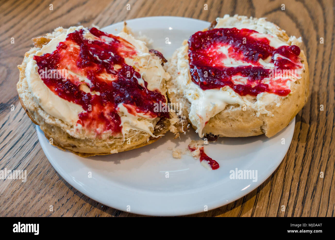 Vista ravvicinata di scones rabboccato con clotted cream e confettura di lamponi. Foto Stock