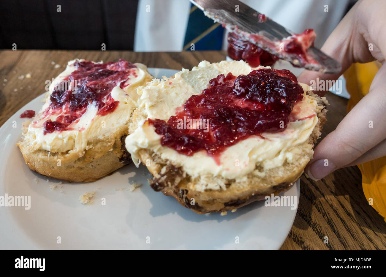 Vista ravvicinata di scones rabboccato con clotted cream e confettura di lamponi. Foto Stock