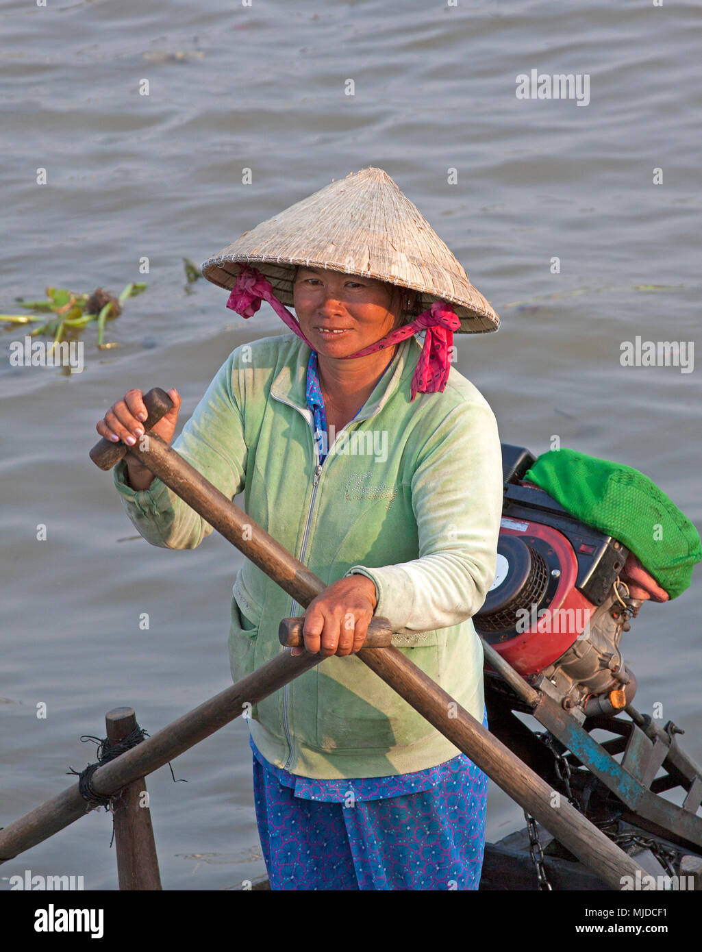 Donna che indossa il bambù hat paddling una barca attraverso il fiume Mekong in Vietnam. Foto Stock