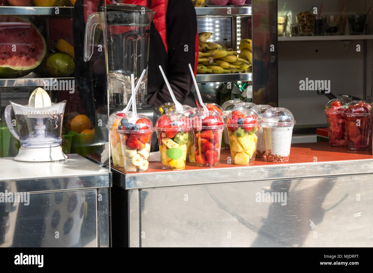 Fresca frutta affettata in bicchieri di plastica venditore Smoothie Stall Foto Stock